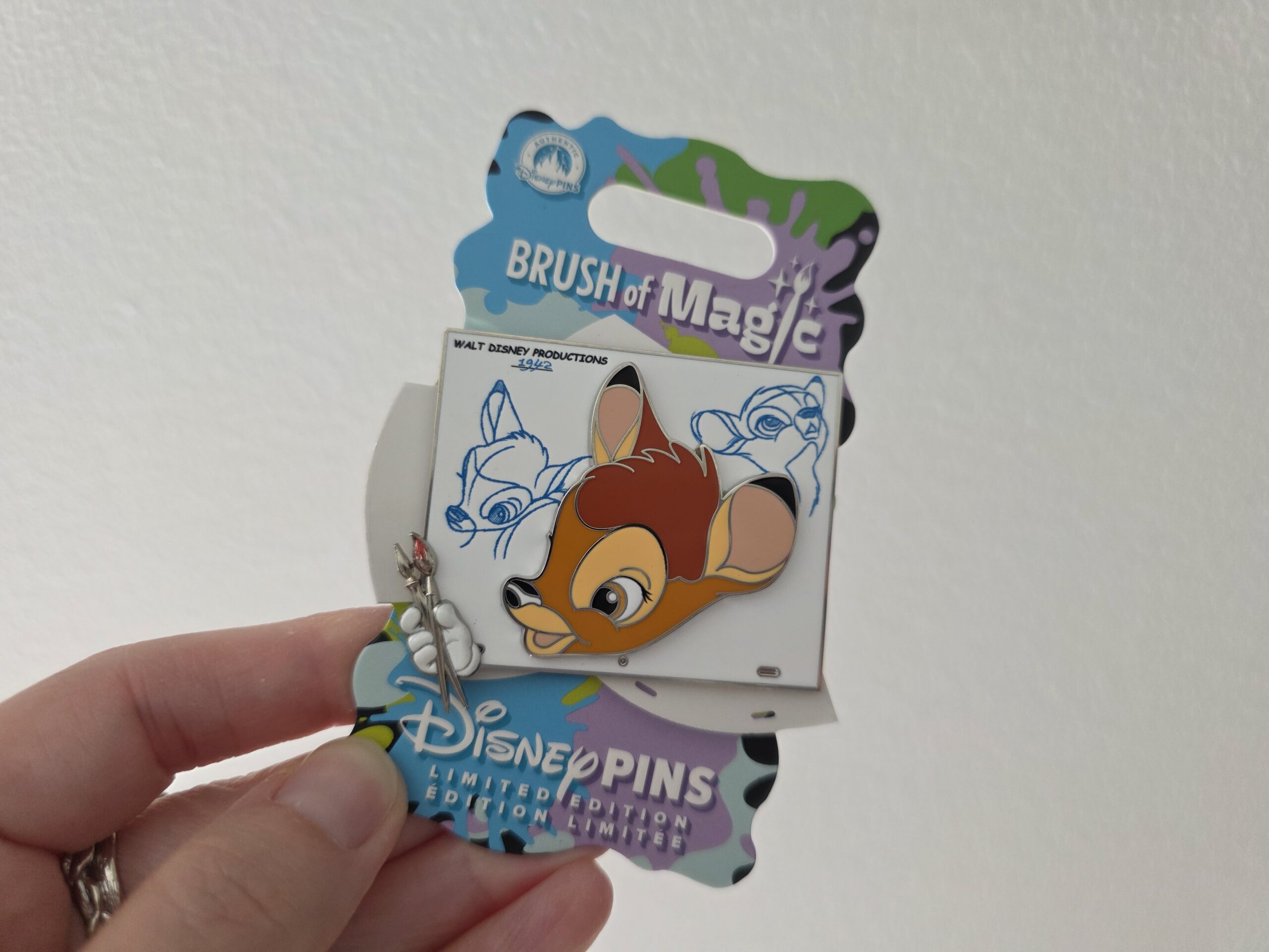 Hand holding the Bambi Brush of Magic Disney pin